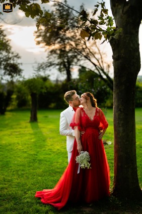 A newly married couple poses for a romantic portrait at Agriturismo Corte Priore in Calino, Italy. The photo captures the couple outdoors at the venue.